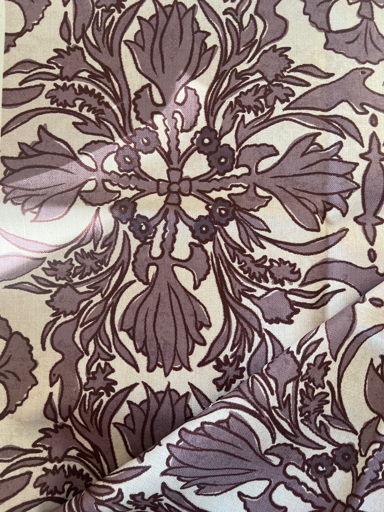 A close-up view of a vintage scarf fabric with a detailed, patterned design featuring floral and geometric elements in a kaleidoscope style.