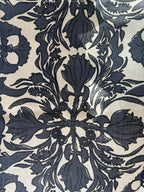 A piece of vintage scarf fabric with a floral and passageway pattern in black and beige colors.