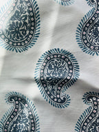 Close-up of a fabric with a paisley pattern featuring teardrop shapes in blue on a white background.