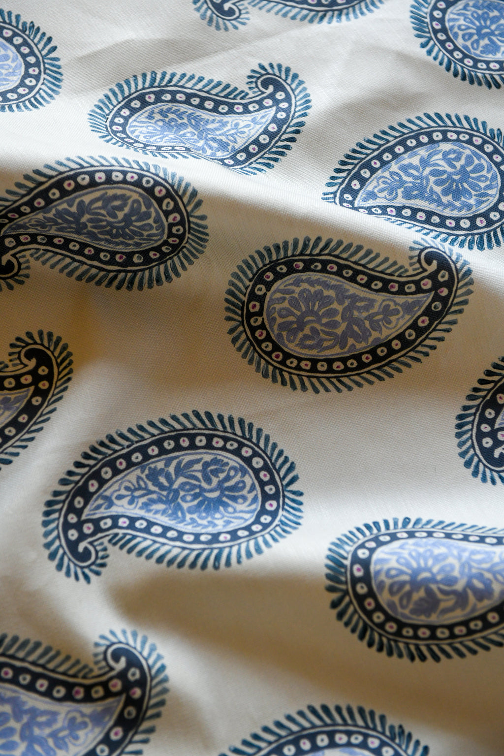 Close-up of a textile fabric with a paisley pattern in blue and white colors.