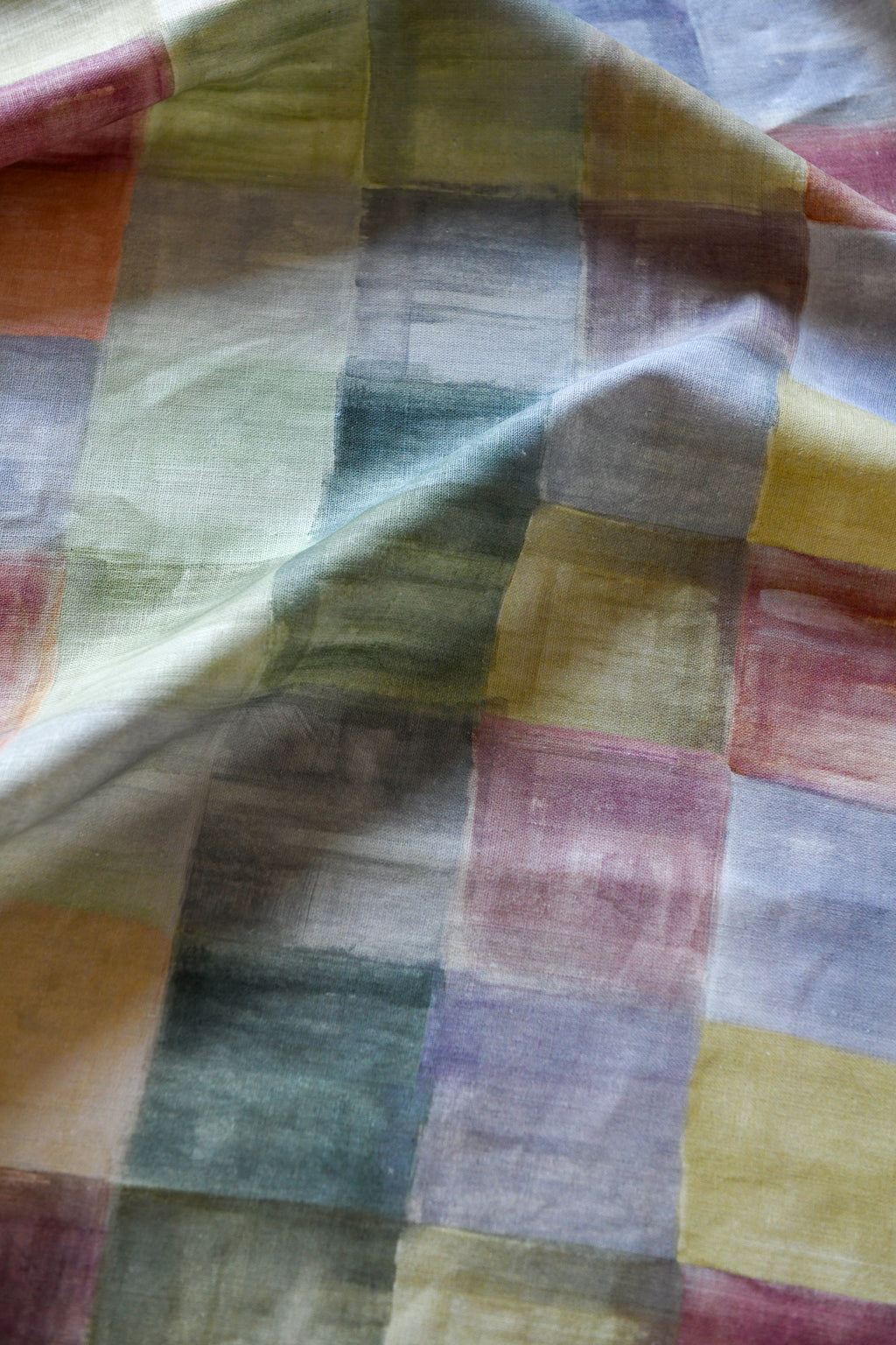 Close-up of a plaid fabric with a pattern of various colors including blue, green, pink, and yellow.