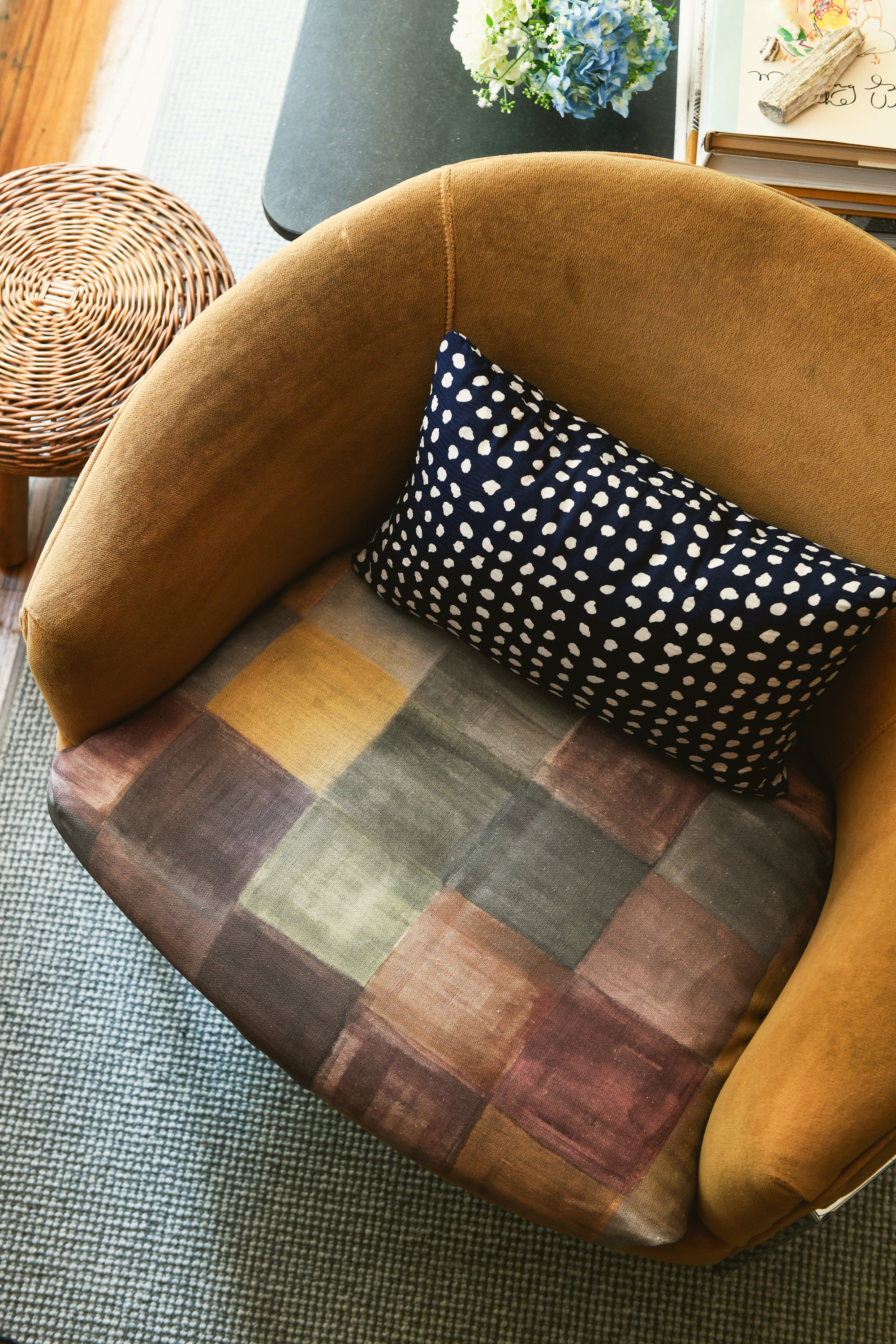 A checkered pattern fabric pillow on a brown armchair.
