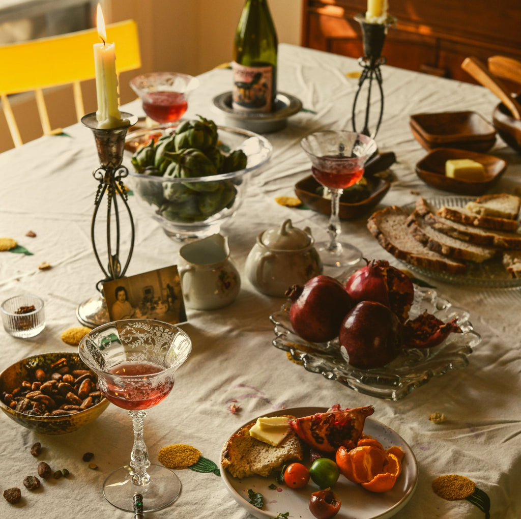 Dining table set with food, drinks, and decorative elements on a white tablecloth.