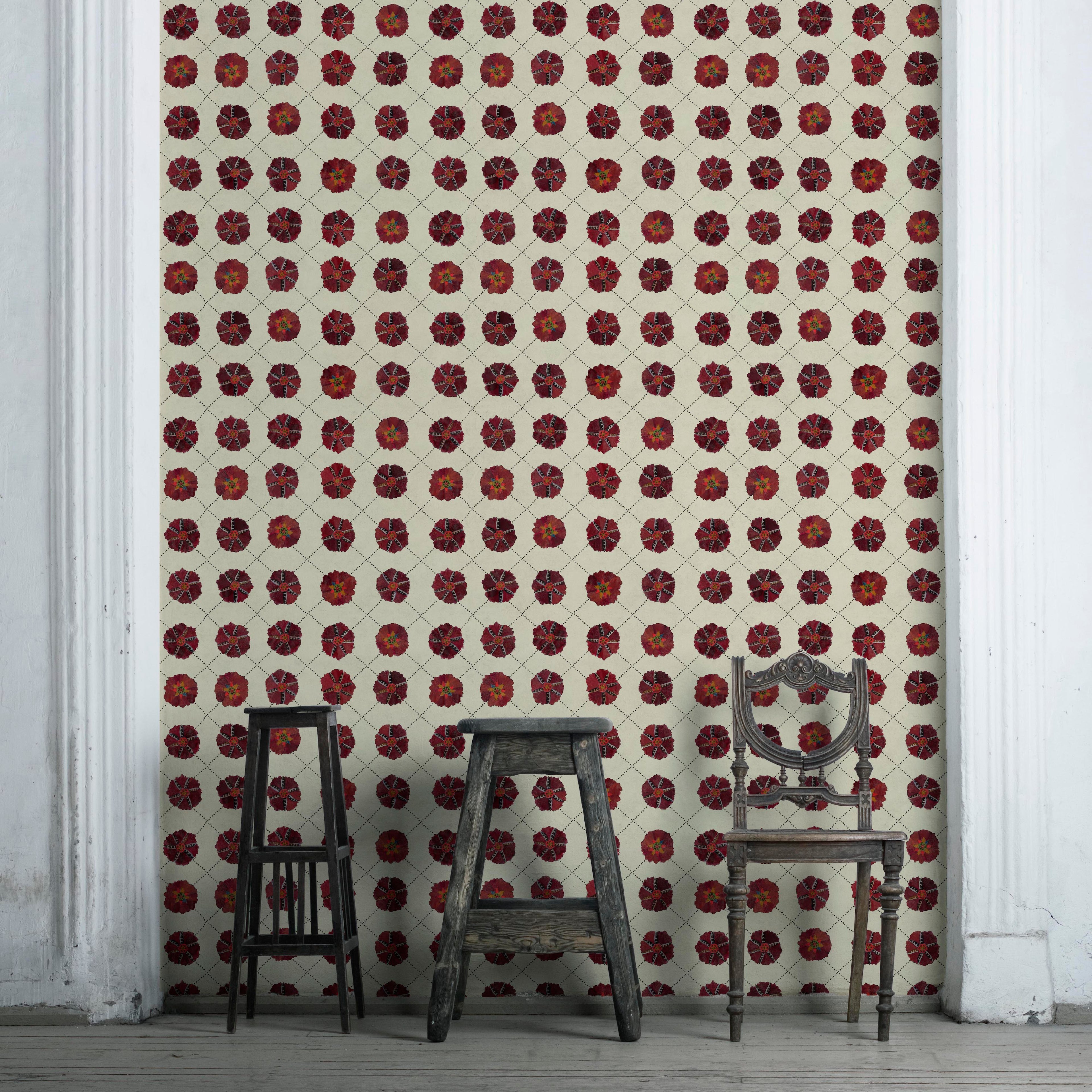A room with Suzani wallpaper featuring a geometric pattern in red and white colors. Two chairs and a small table are placed against the wall, highlighting the wallpaper.