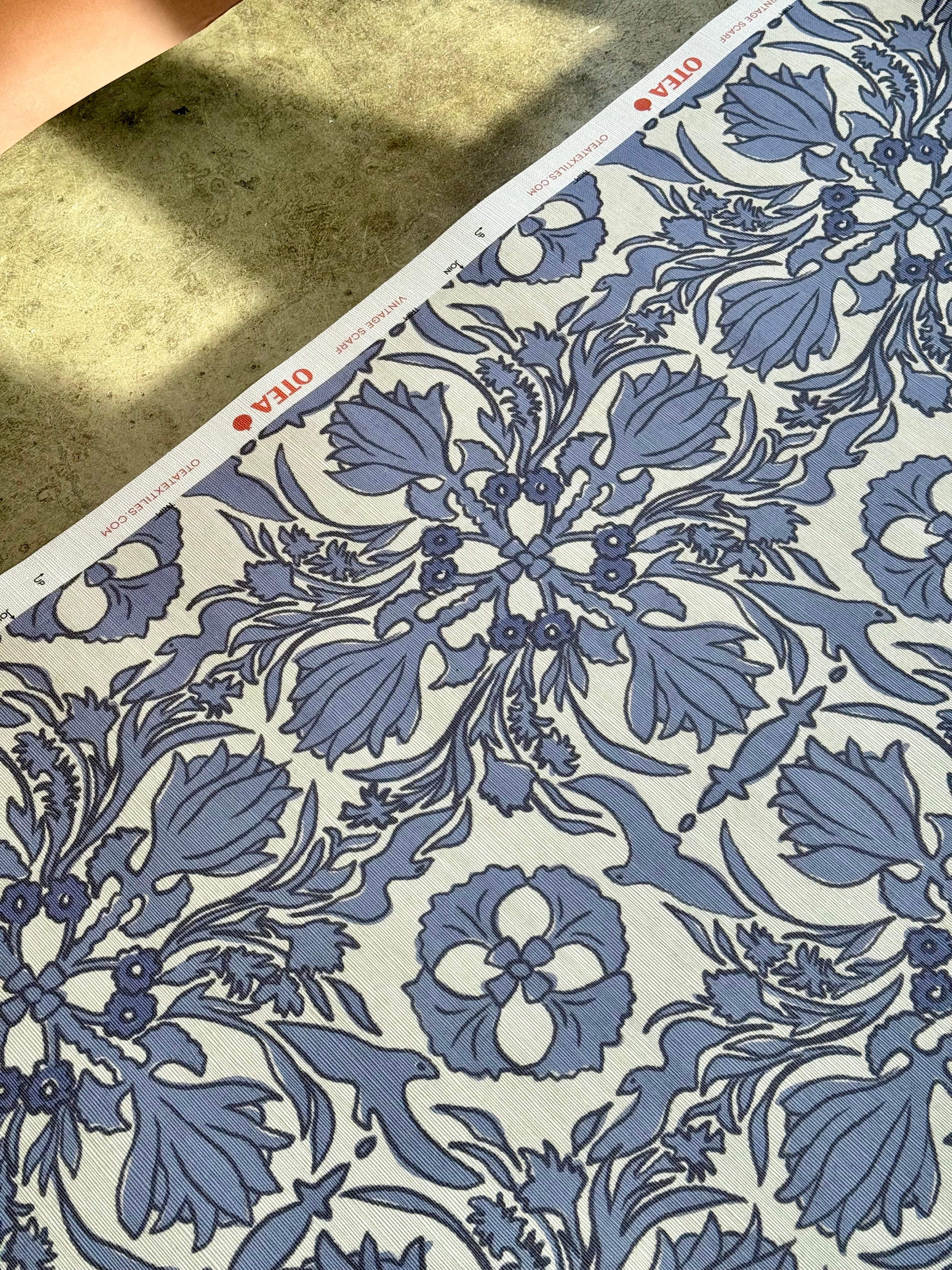 A close-up view of a vintage scarf wallpaper featuring a floral pattern in blue and white colors.
